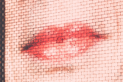 Photo of face and lips projected onto a brick wall. By Arun Kuchibhotla, from Unsplash