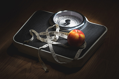 Weighing scales with measuring tape and an apple