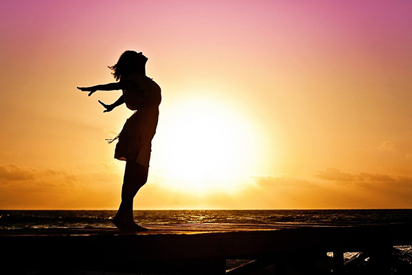 Side profile silhouette of woman by sea with sun behind