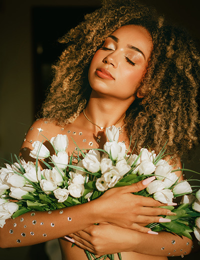 Woman holding white flowers to her chest - Photo by Evellyn Cardoso on Pexels