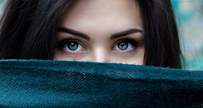 Photo of a woman's face half hidden behind a scarf - by StockSnap from Pixabay 