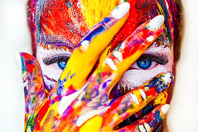 Woman in bright face paint with hand over face