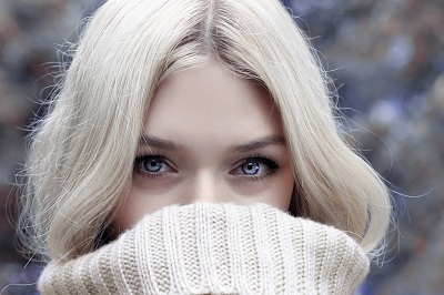 Woman covering nose with cream jumper