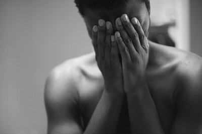 Topless man covering his face