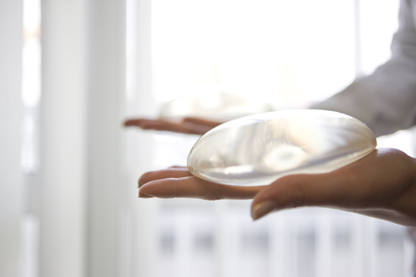 Plastic Surgeon holding a silicone breast implant